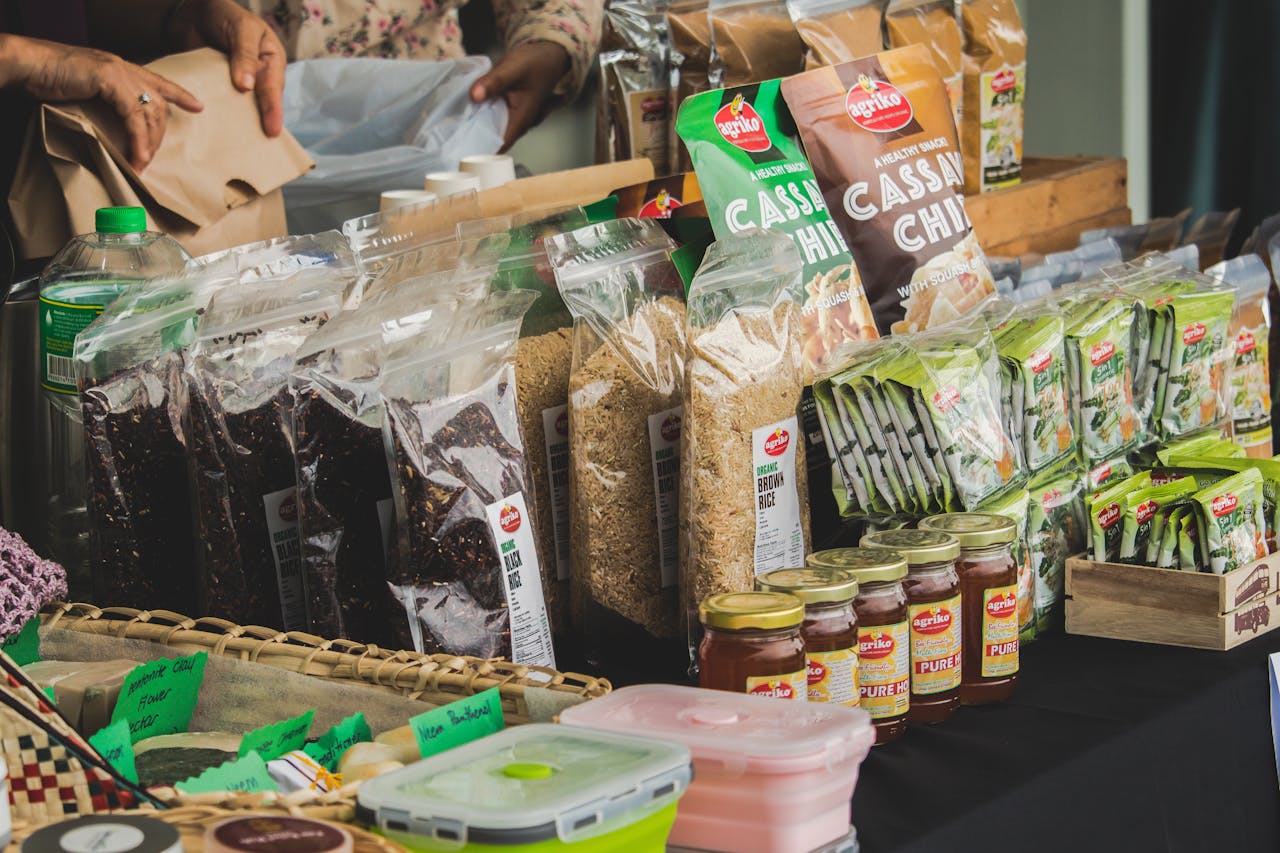who-we-are An assortment of packaged foods displayed on a market stall indoors, showcasing variety.
